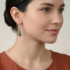 Woman wearing a black-gold enamel silver earring with a neutral background