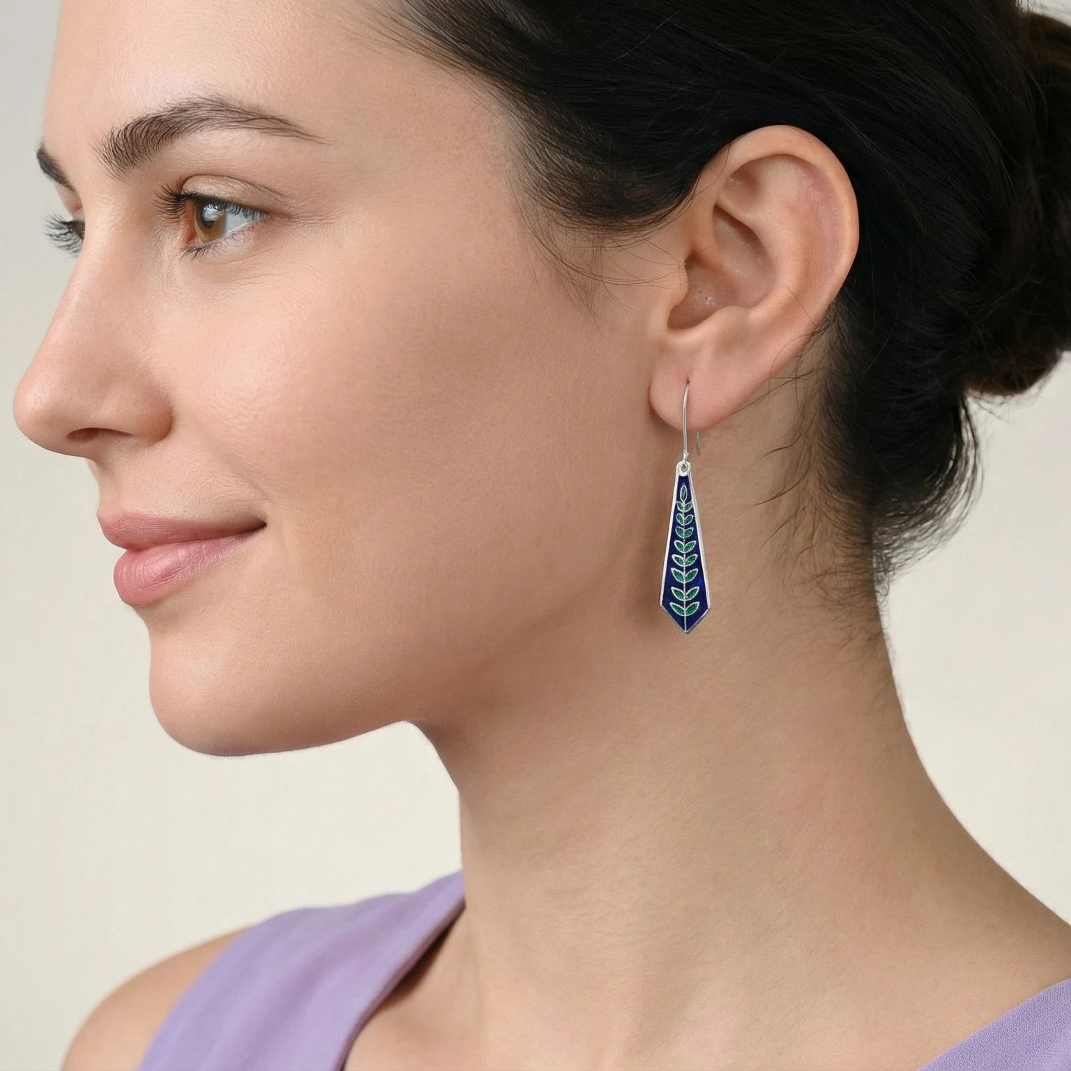 Woman wearing blue enamel silver earring with a neutral background