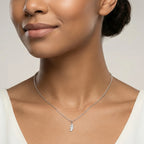 Closeup of a female wearing a silver necklace with a small feather pendant against a neutral background