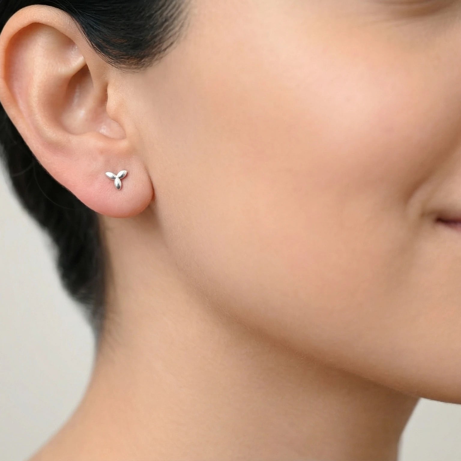 Closeup of a woman with dark hair wearing silver flower stud earring