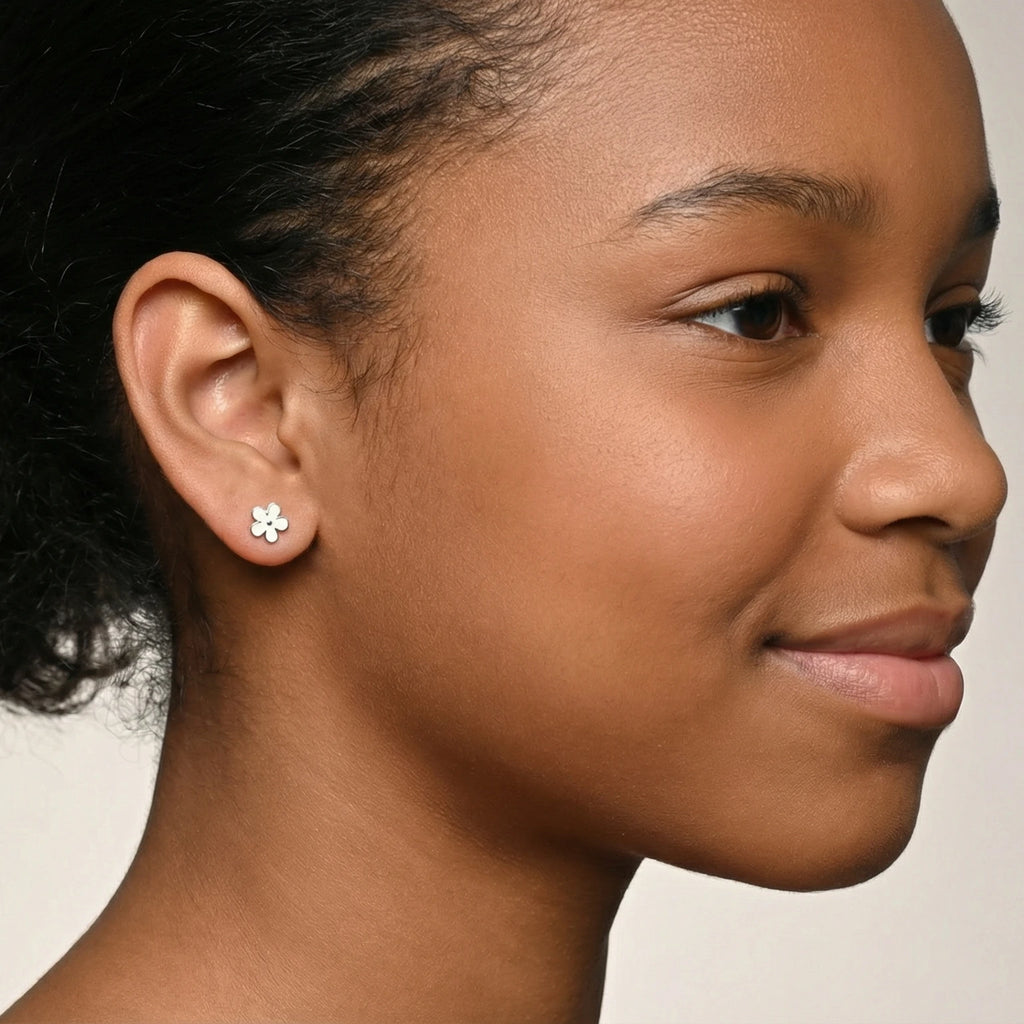 Close-up of a girl wearing a silver floral stud earring against a plain background