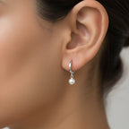 Close-up of an ear wearing a silver hoop earring with a fresh water pearl charm 