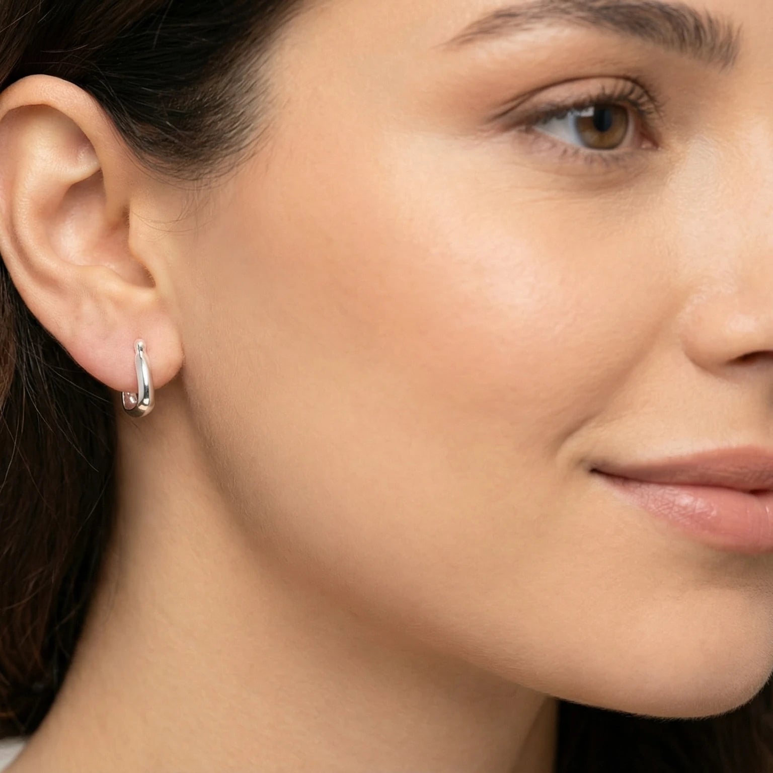 Close-up of a woman wearing a Silver Geometric French Lock Hoop Earring.