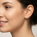 Close-up of a woman wearing a hammered French lock silver hoop earring with a blurred background