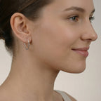 Close-up of a female wearing a silver hammered half hoop stud earring with a neutral background