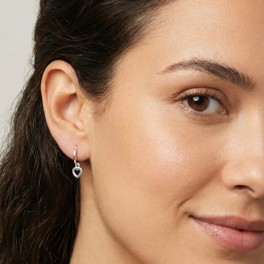 Close-up of a woman wearing a heart-shaped charm hoop earring.