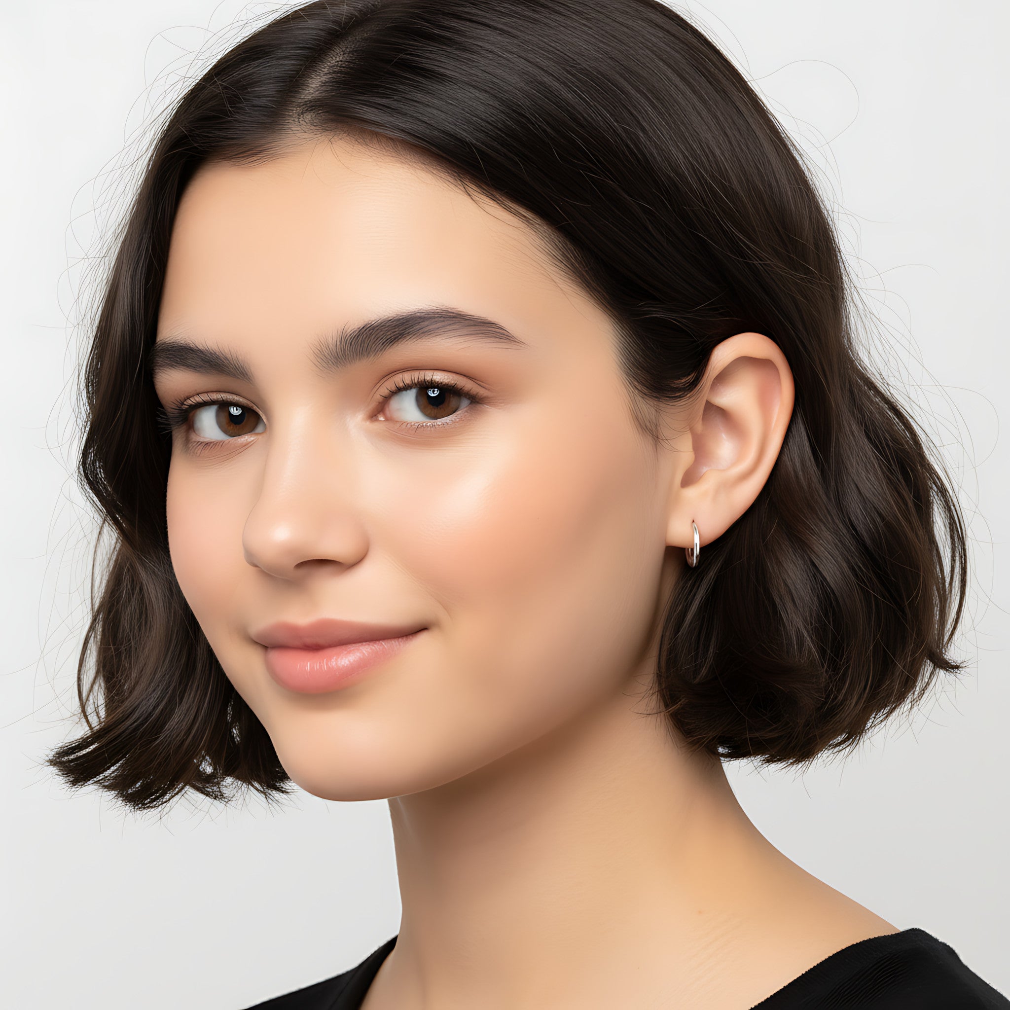 Close-up of a young girl with styled hair and silver hoop earrings against a neutral background