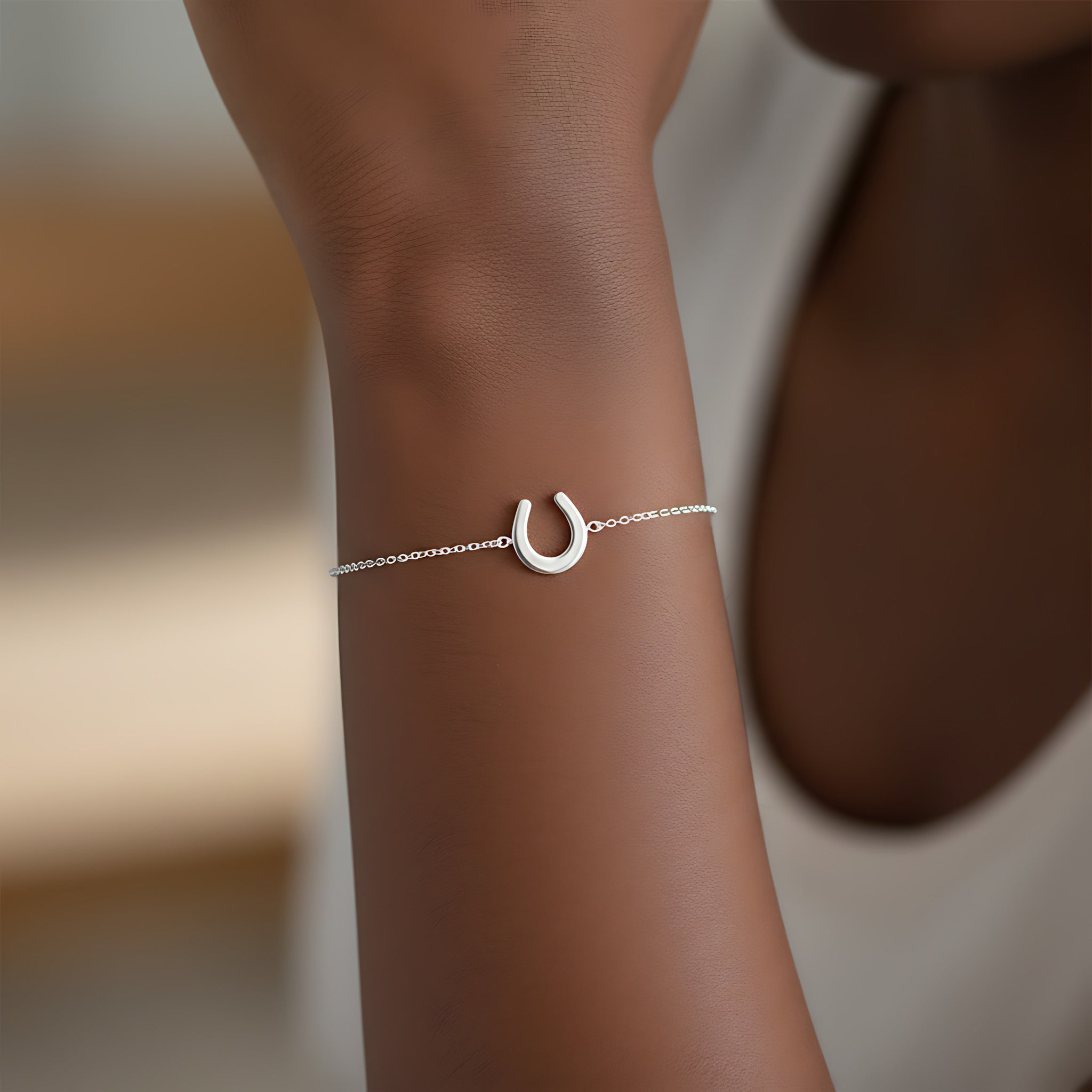 Silver bracelet with a horseshoe charm on a wrist against a blurred background