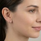 Close-up of a woman wearing a silver knot half hoop stud earring with a neutral background