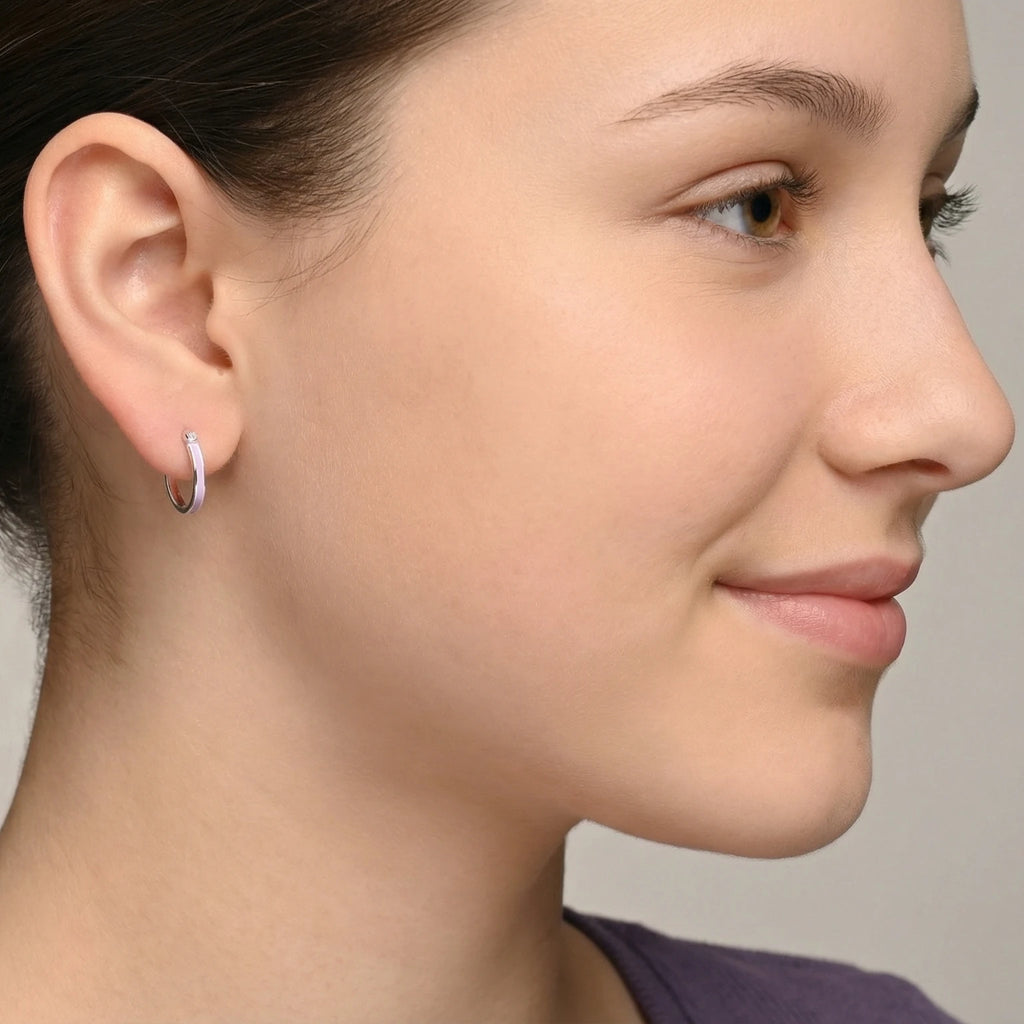 Close-up of a girl wearing a silver hoop earring having a lavender colour accent against a plain background