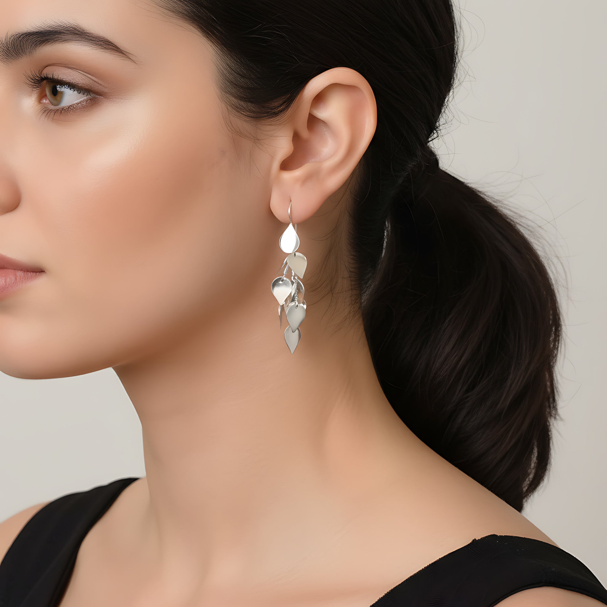 Close-up of a woman wearing silver leaflet dangle earring with a neutral background