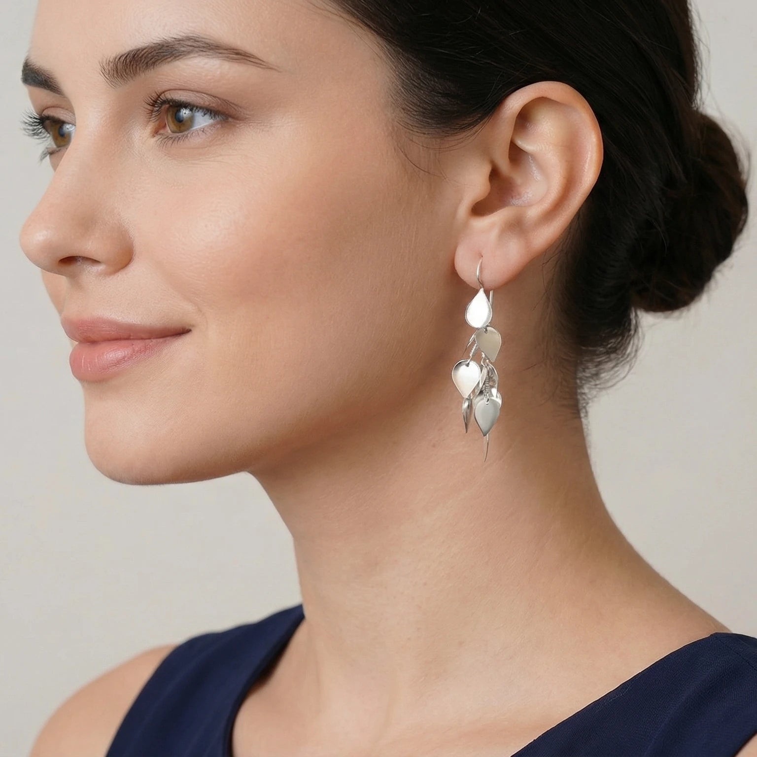 Close-up of a woman wearing silver leaflet dangle earring with a neutral background