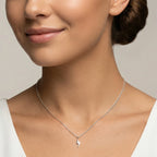 Closeup of a female wearing a silver necklace with a small lightning bolt pendant against a neutral background