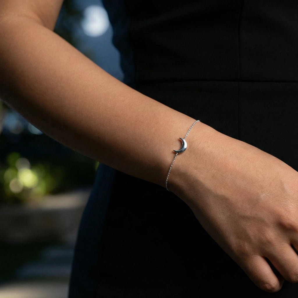 Female wearing a black dress and a silver bracelet with a moon design on a blurred background