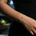 Female wearing a black dress and a silver bracelet with a moon design on a blurred background