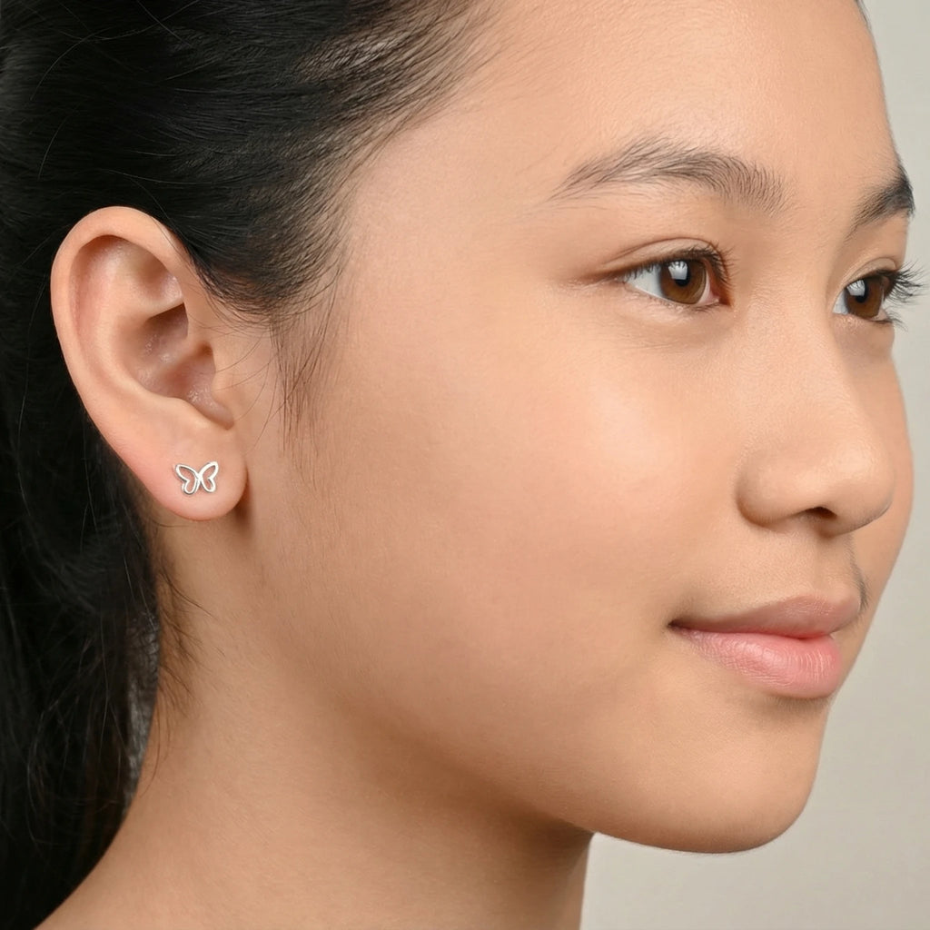 Close-up of a young girl with styled hair and silver butterfly stud earrings against a neutral background
