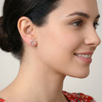 Closeup of a woman with a floral red top and heart-shaped stud earrings