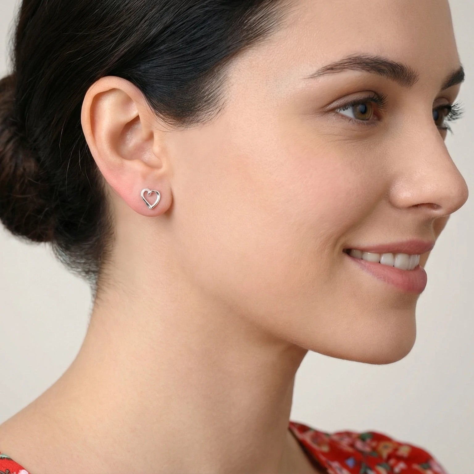 Closeup of a woman with a floral red top and heart-shaped stud earrings
