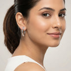 Woman with styled hair wearing a shiny silver petal-shaped stud earring against a plain background