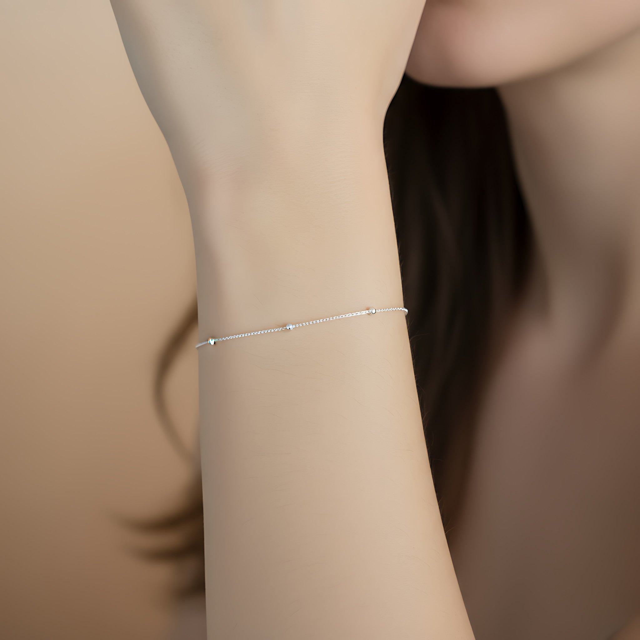 Silver satellite bracelet on a person's wrist with a blurred background