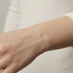 Silver LT satellite bracelet on a person's wrist with a blurred background