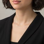Close-up of a person wearing a delicate silver Singapore chain against a neutral background