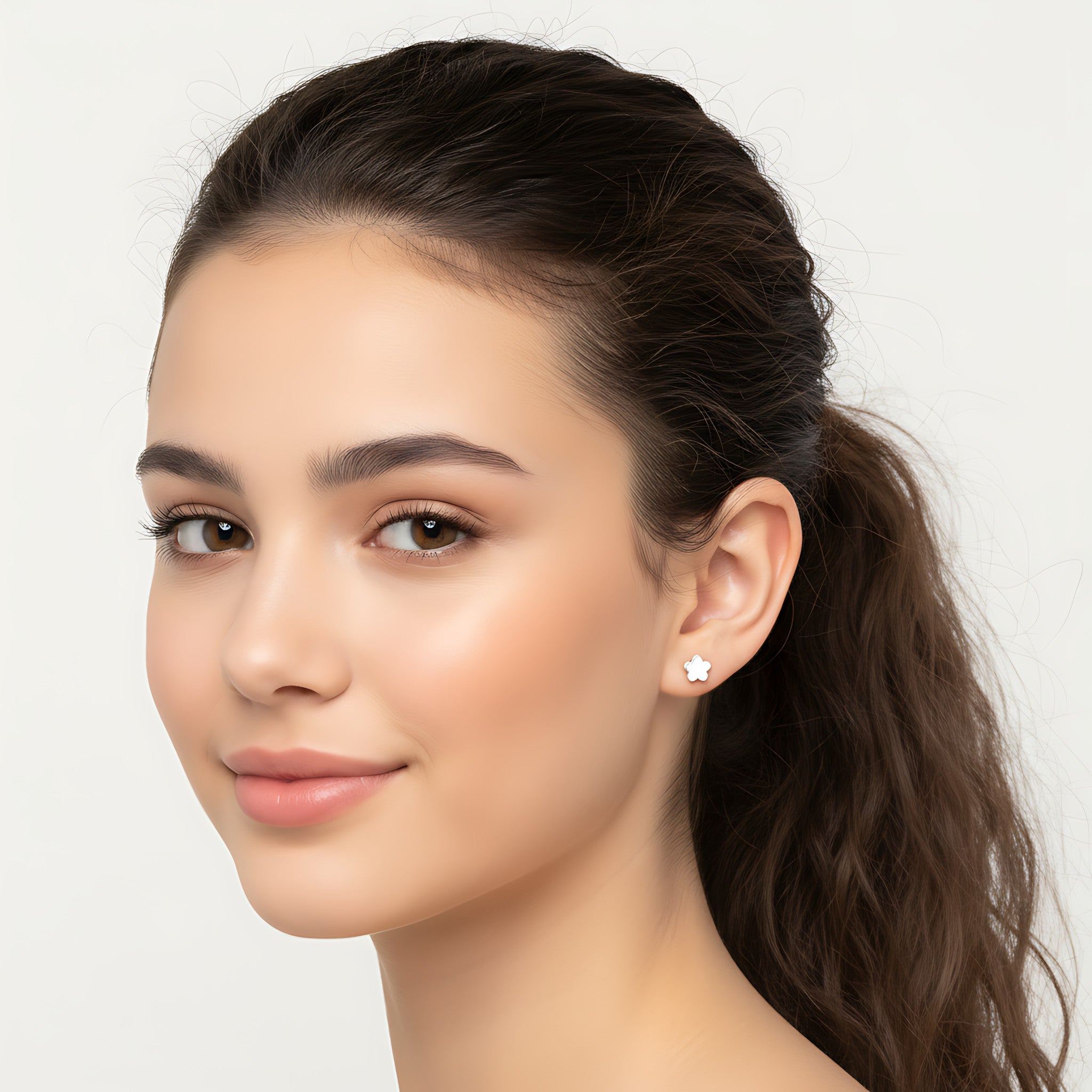 Closeup of a girl wearing a silver flower stud earring on a plain background