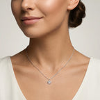Closeup of a female wearing a silver necklace with a small snowflake pendant against a neutral background