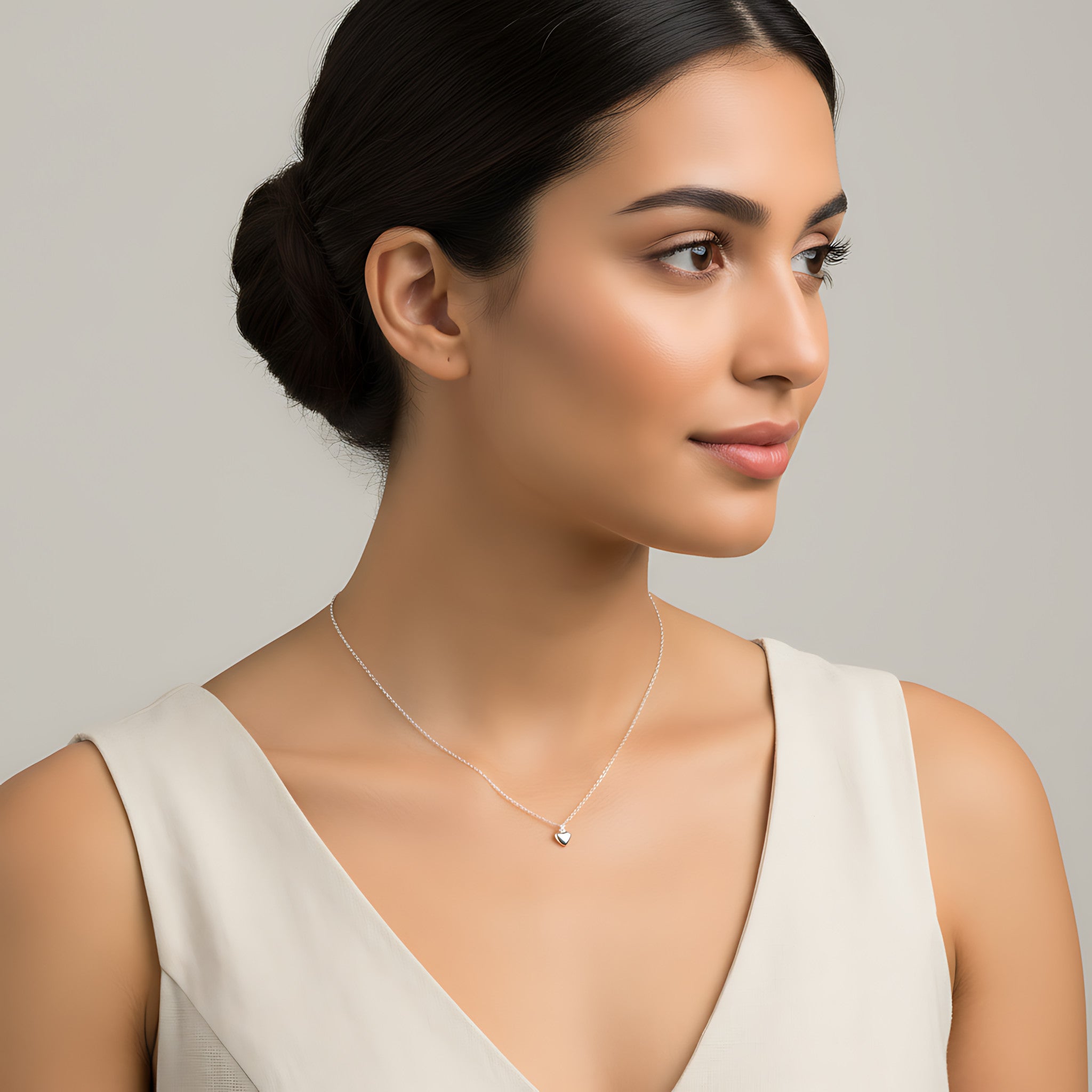 Woman wearing a delicate heart pendant necklace against a neutral background