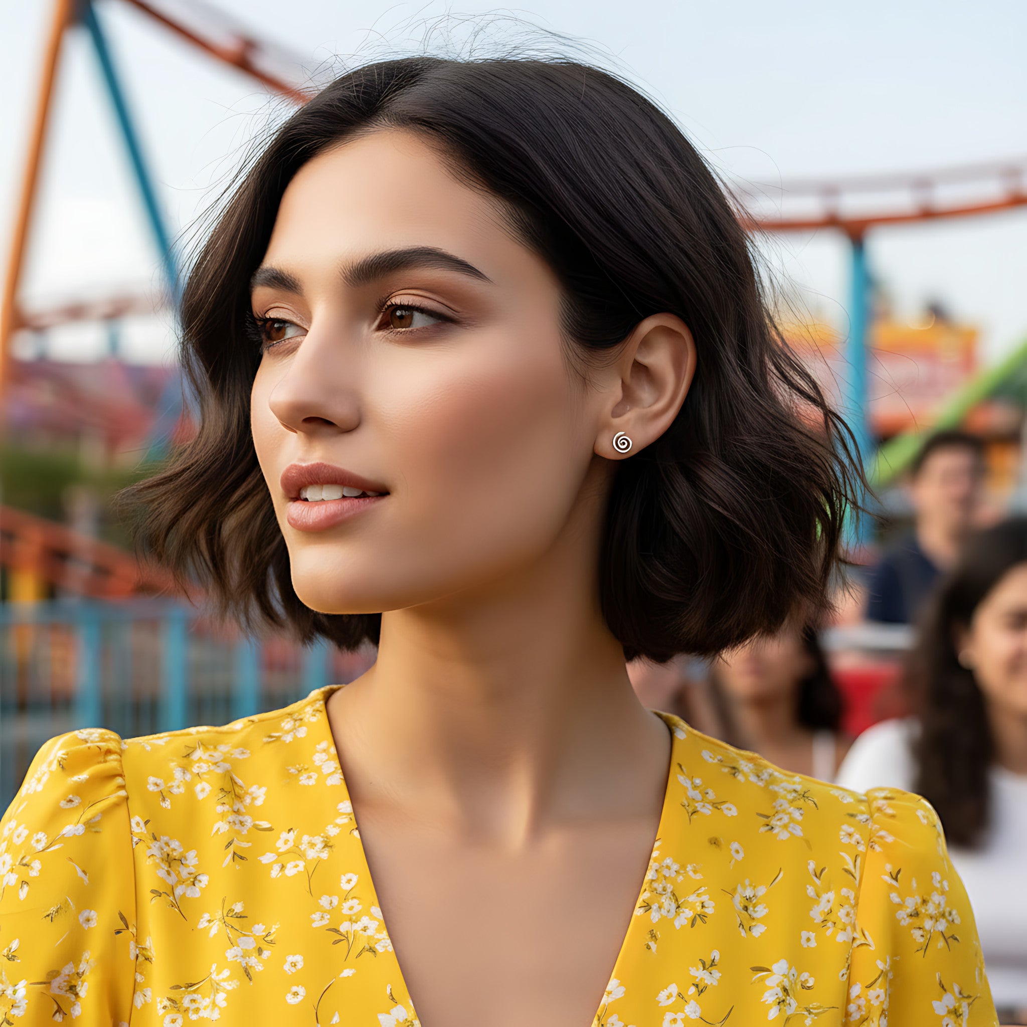 Woman in a yellow floral dress wearing a spiral stud earring with a blurred amusement park background