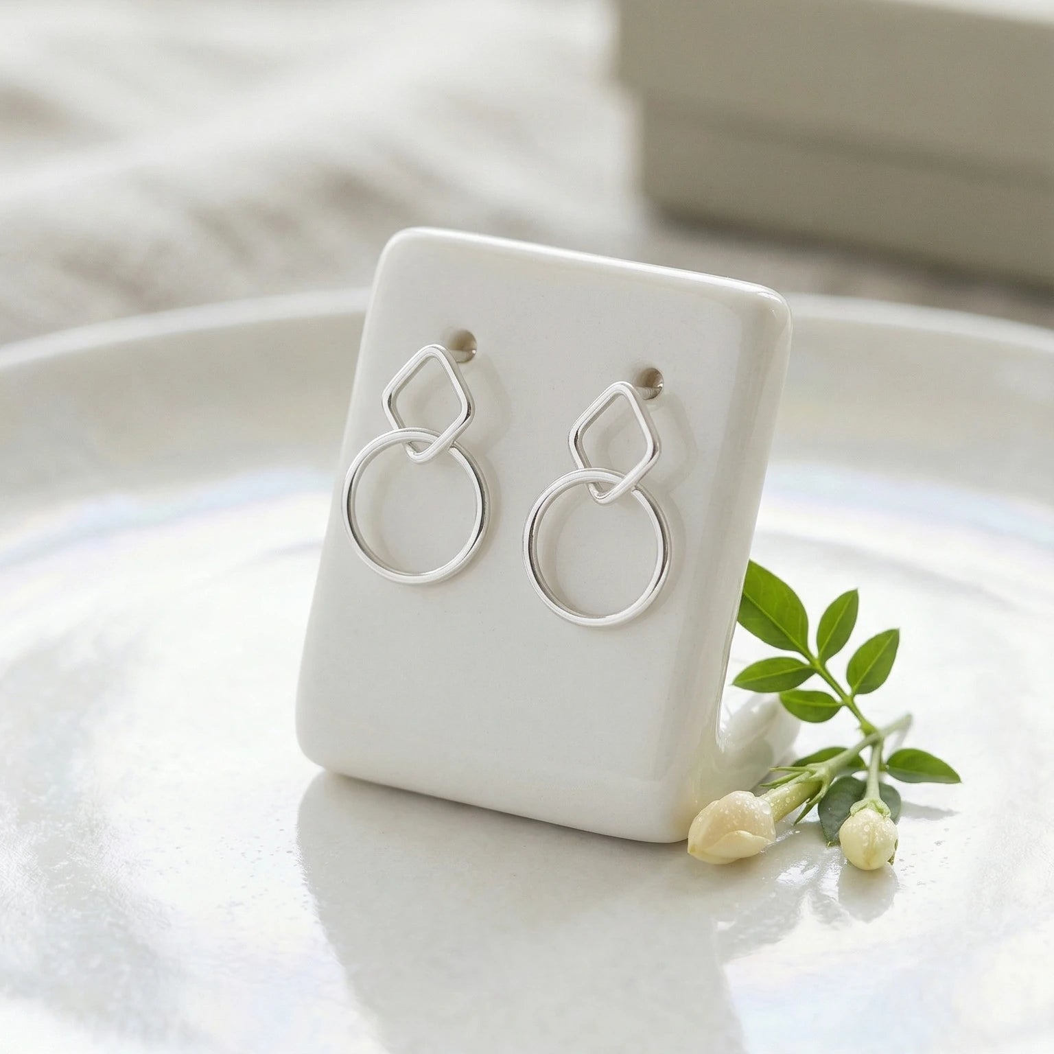 Silver stud earrings on a white stand with a soft background