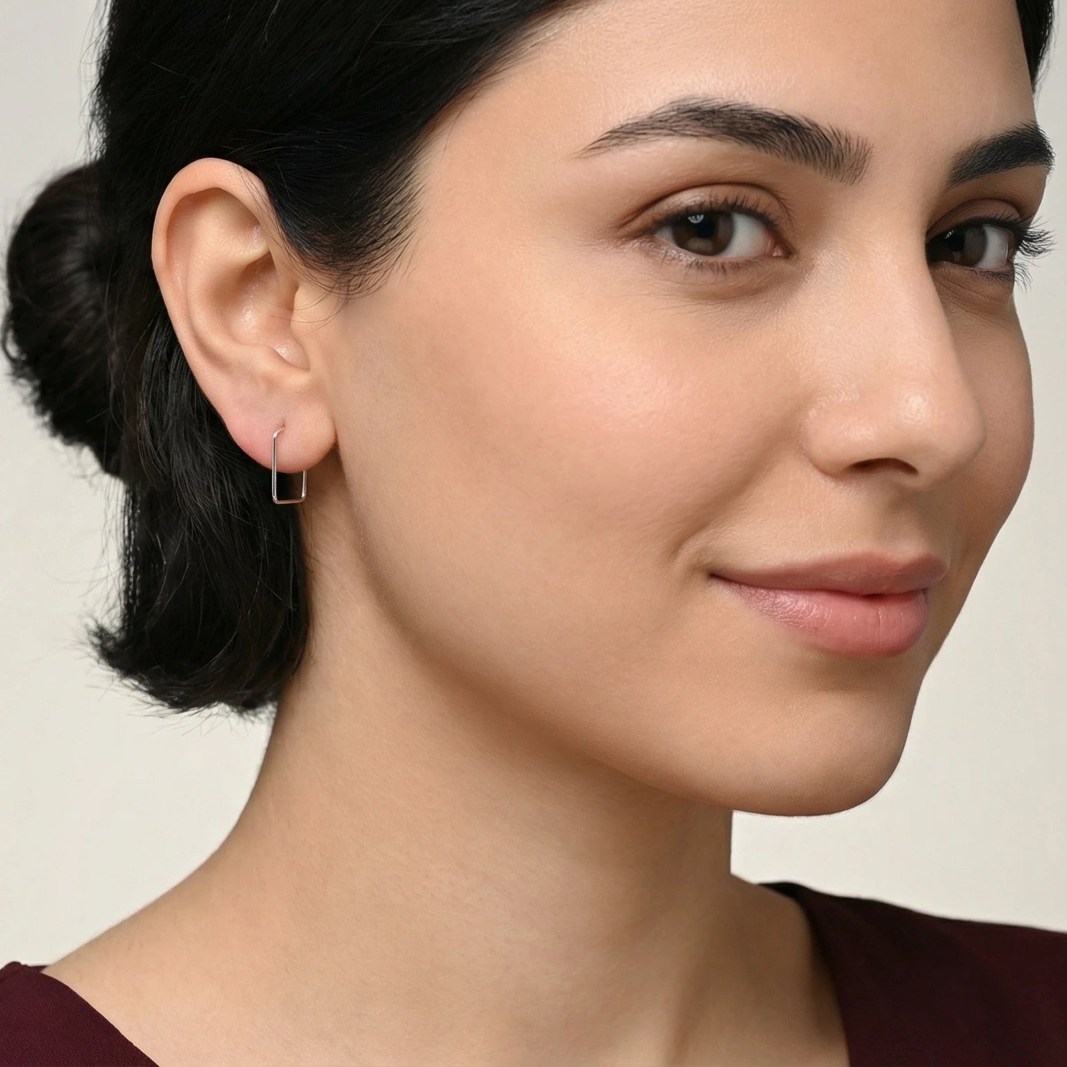 Close-up of a woman wearing a square hoop earring