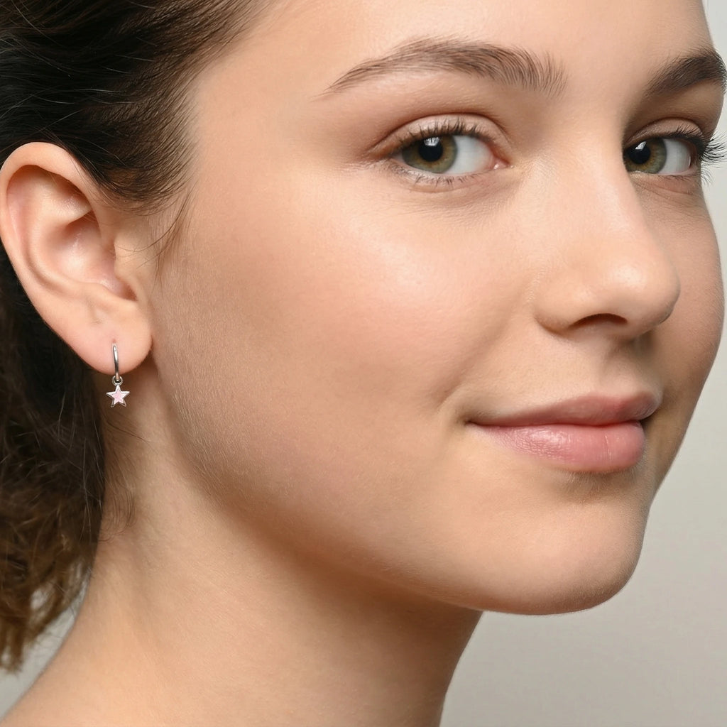 Closeup of a girl wearing a silver hoop earring with a silver star charm on a plain background