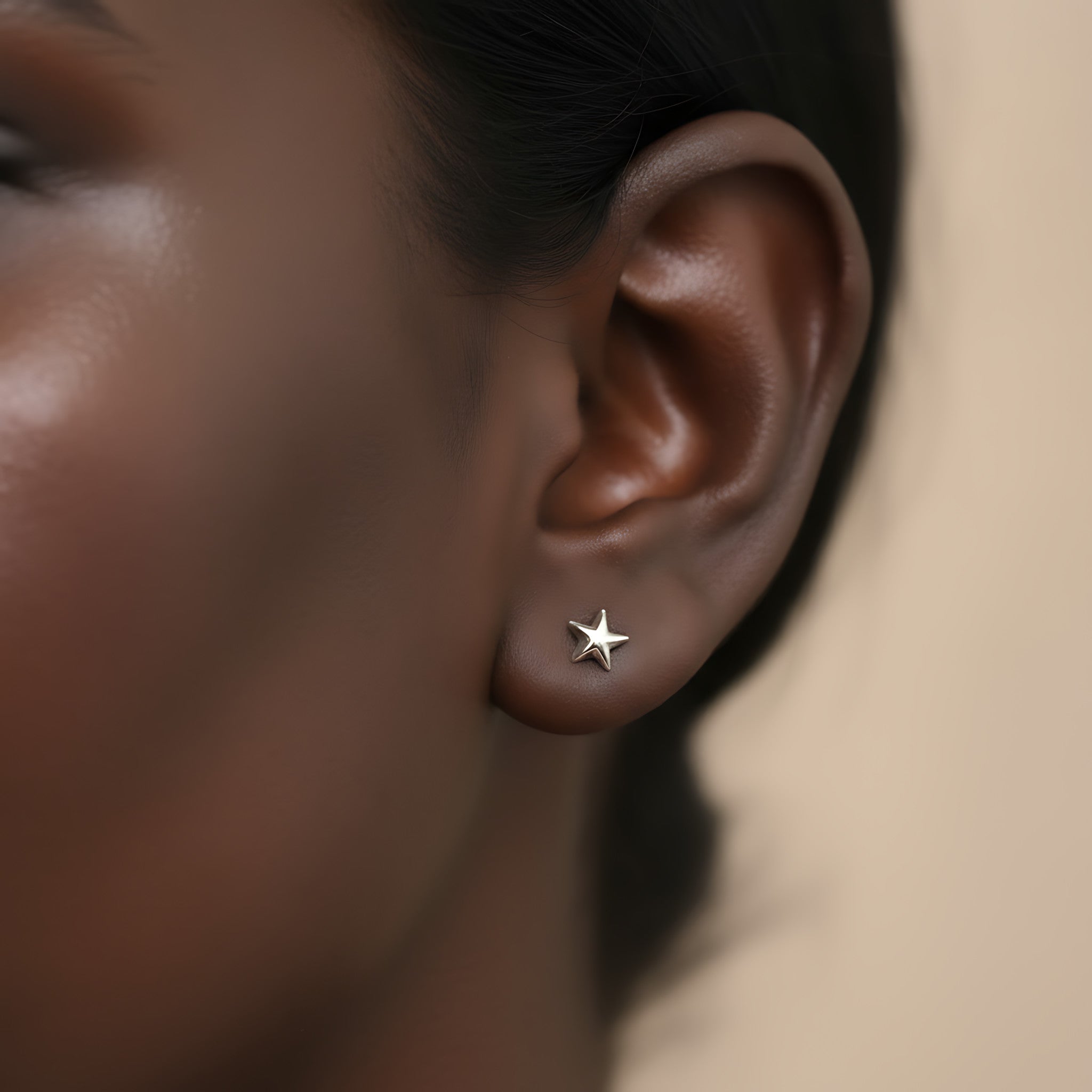Close-up of an ear wearing a star-shaped silver stud earring with a blurred background