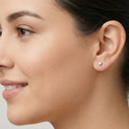 Close-up of a female wearing a star-shaped silver stud earring with a plain background