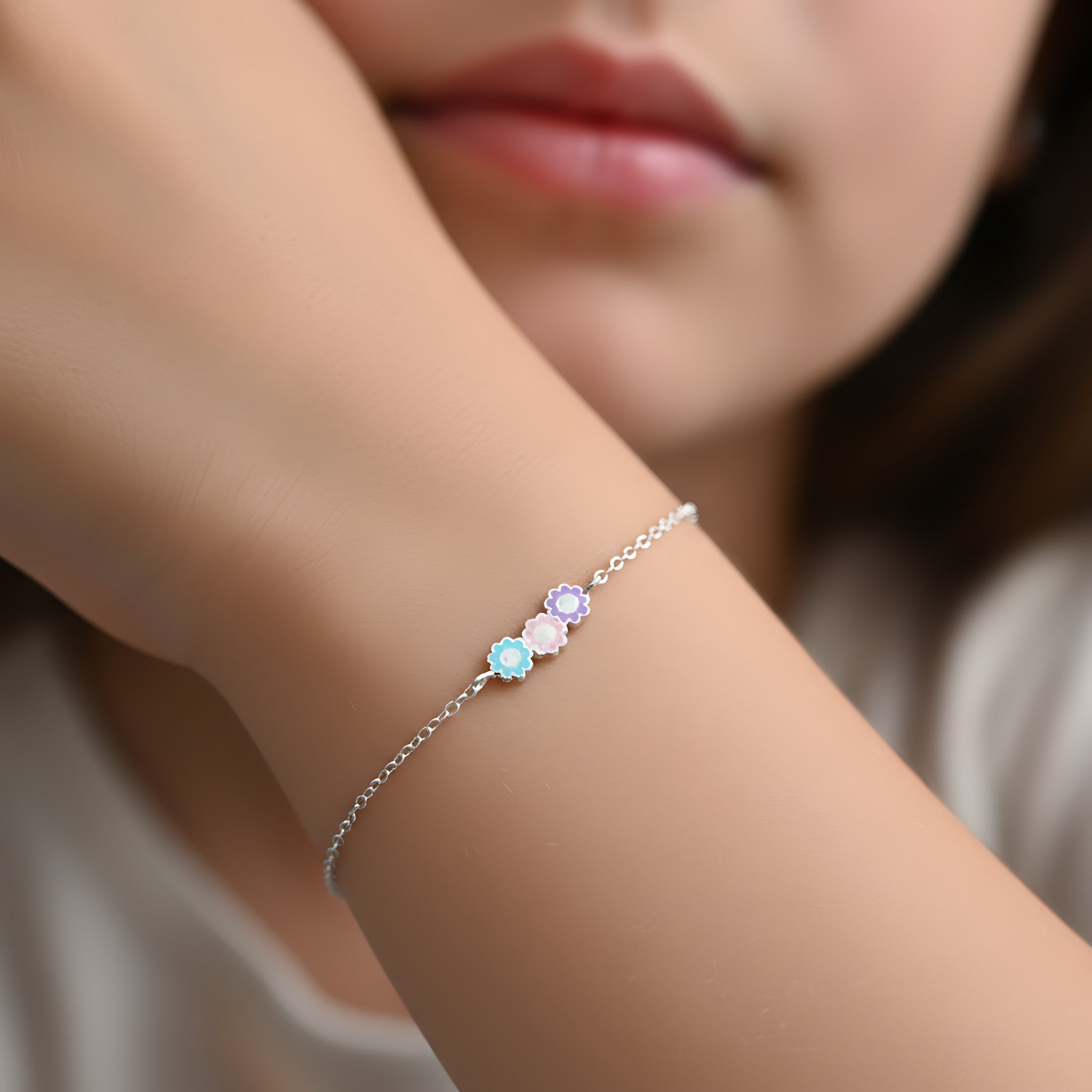 Silver bracelet with 3 daisy flowers on a girl's wrist, blurred background