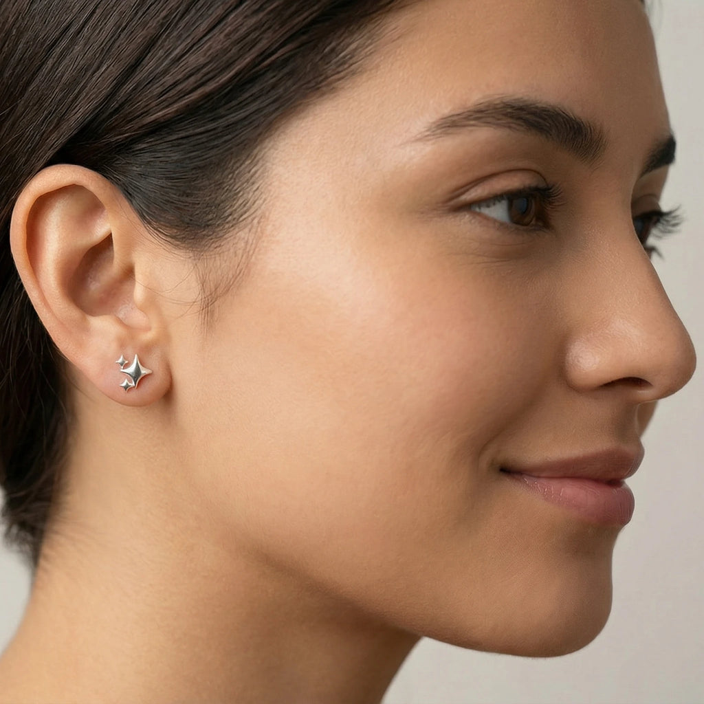 Close-up of a female wearing a triple star-shaped silver stud earring with plain background