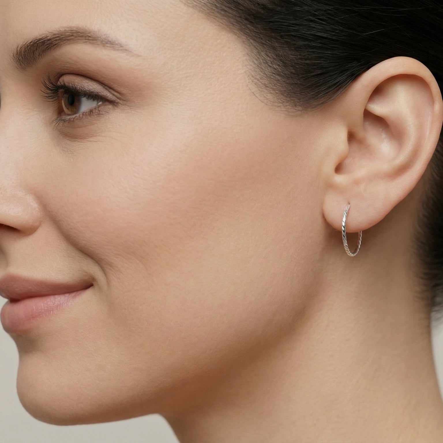 Close-up of a woman wearing twist cut style hoop earring