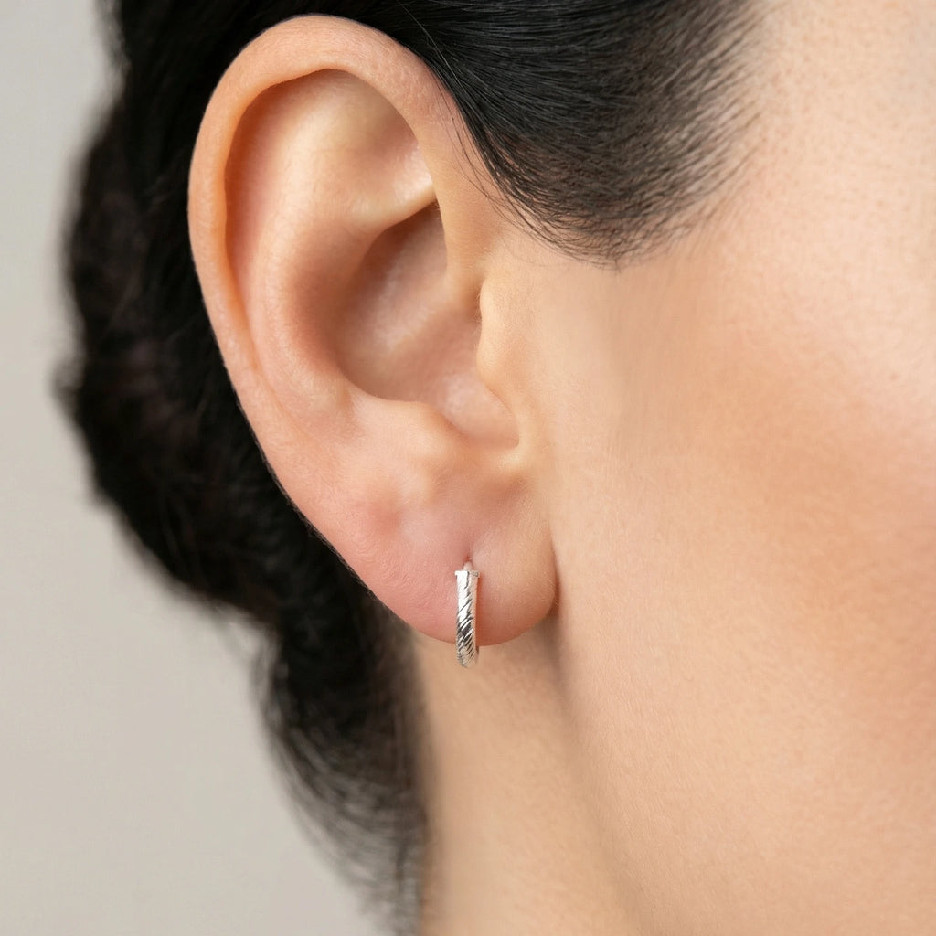 Pair of silver hoop earrings with twisted textured look on a white background