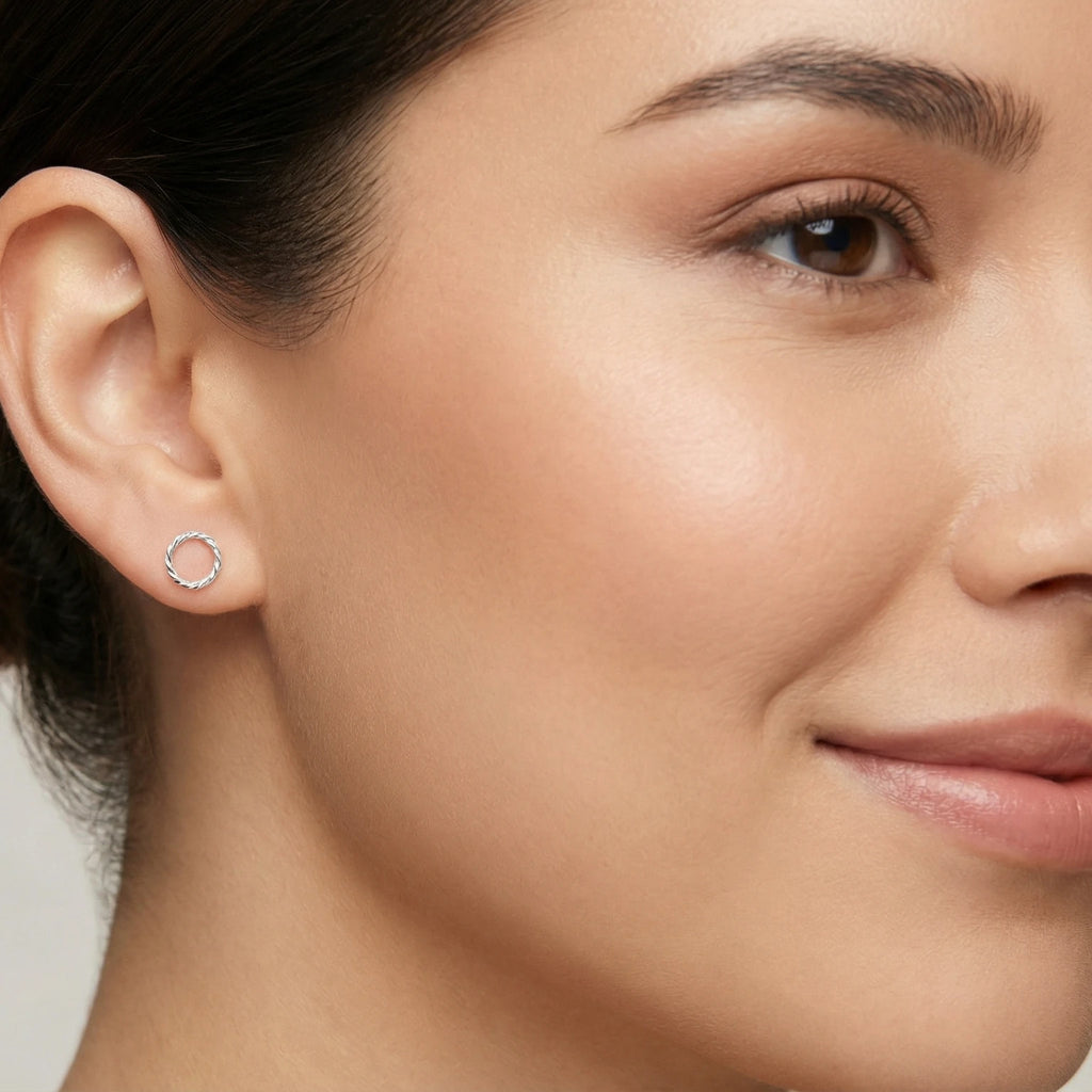 A closeup of a woman wearing twisted circle stud earring