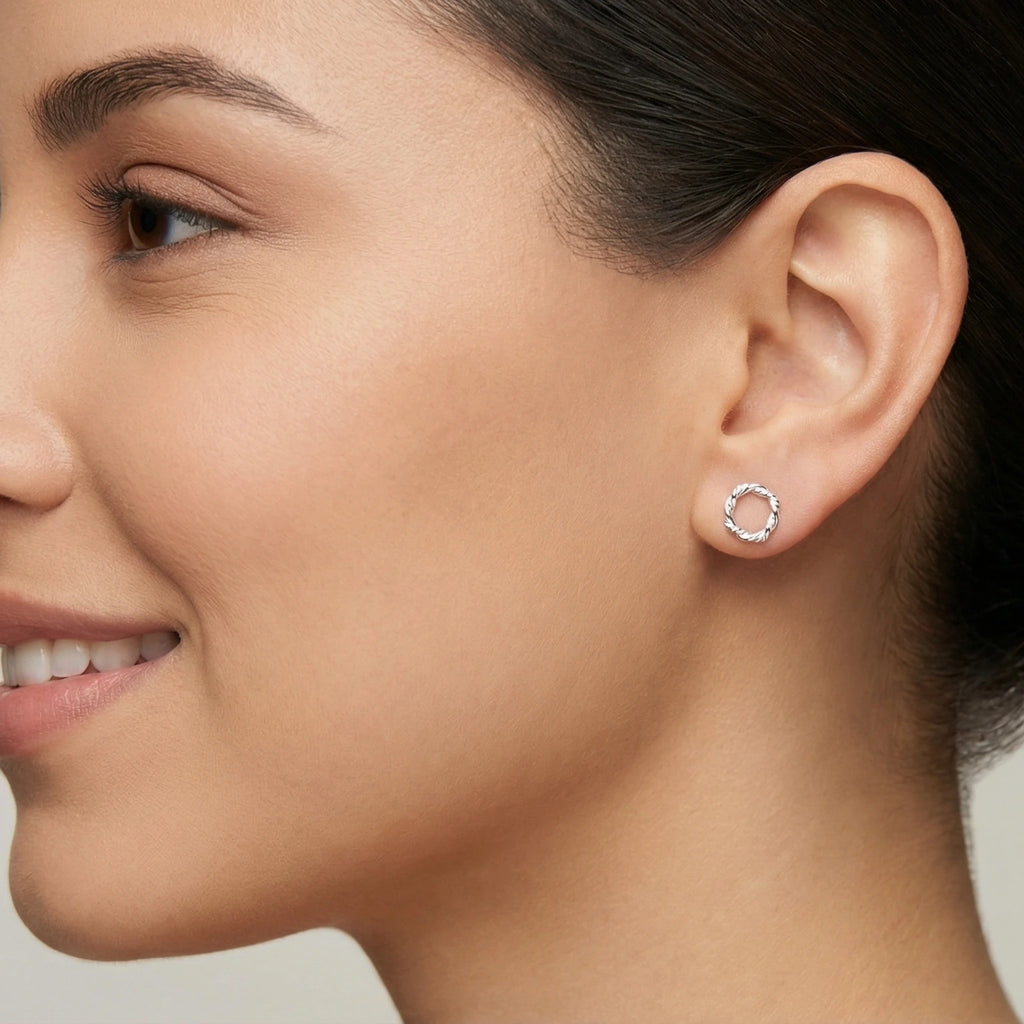 A closeup of a woman wearing silver twisted orbit stud earring
