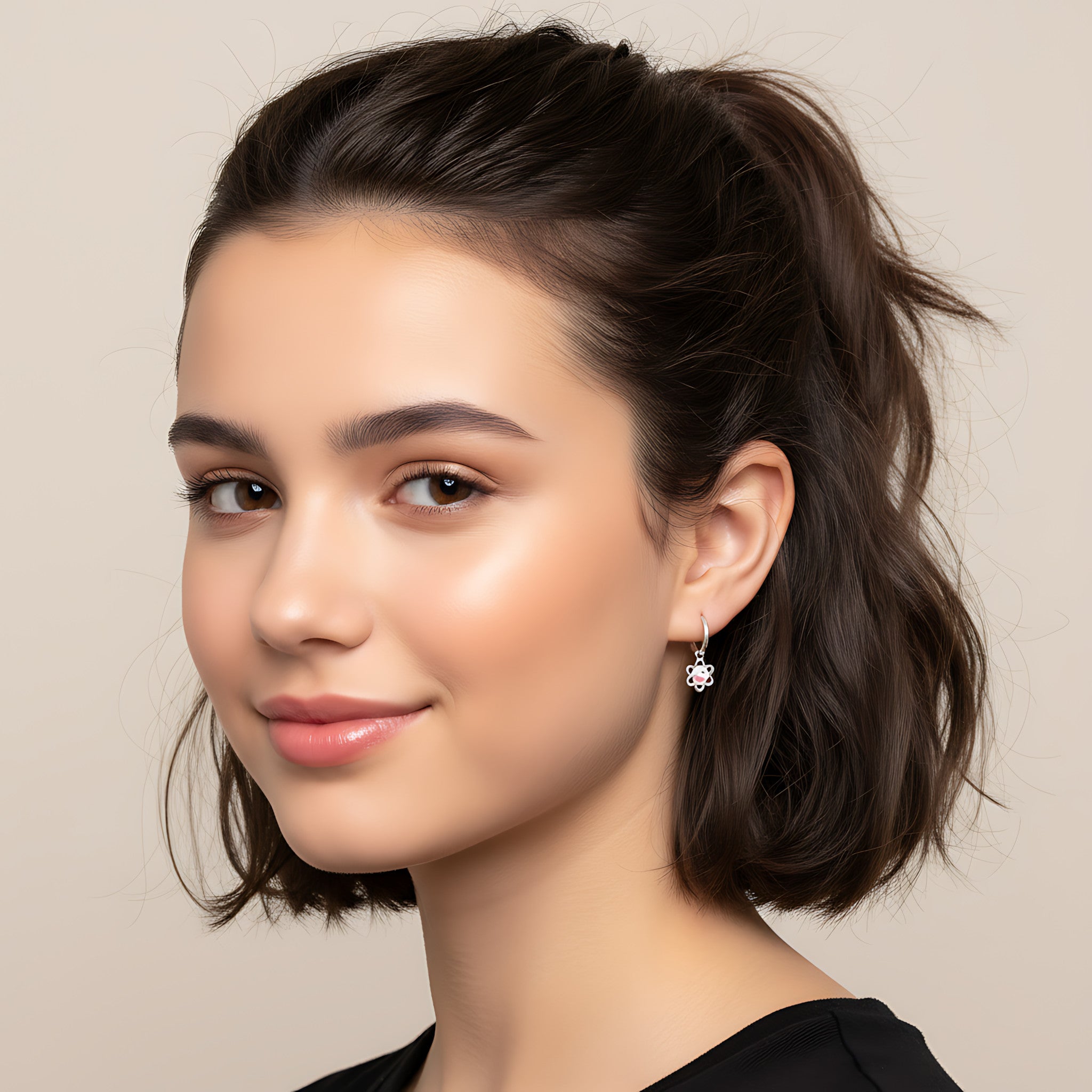 Close-up of a young girl with styled hair and hoop earrings with yin-yang flower charm against a neutral background